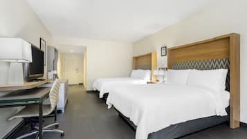 A hotel room with two beds, a desk with a computer, a chair, and a TV.