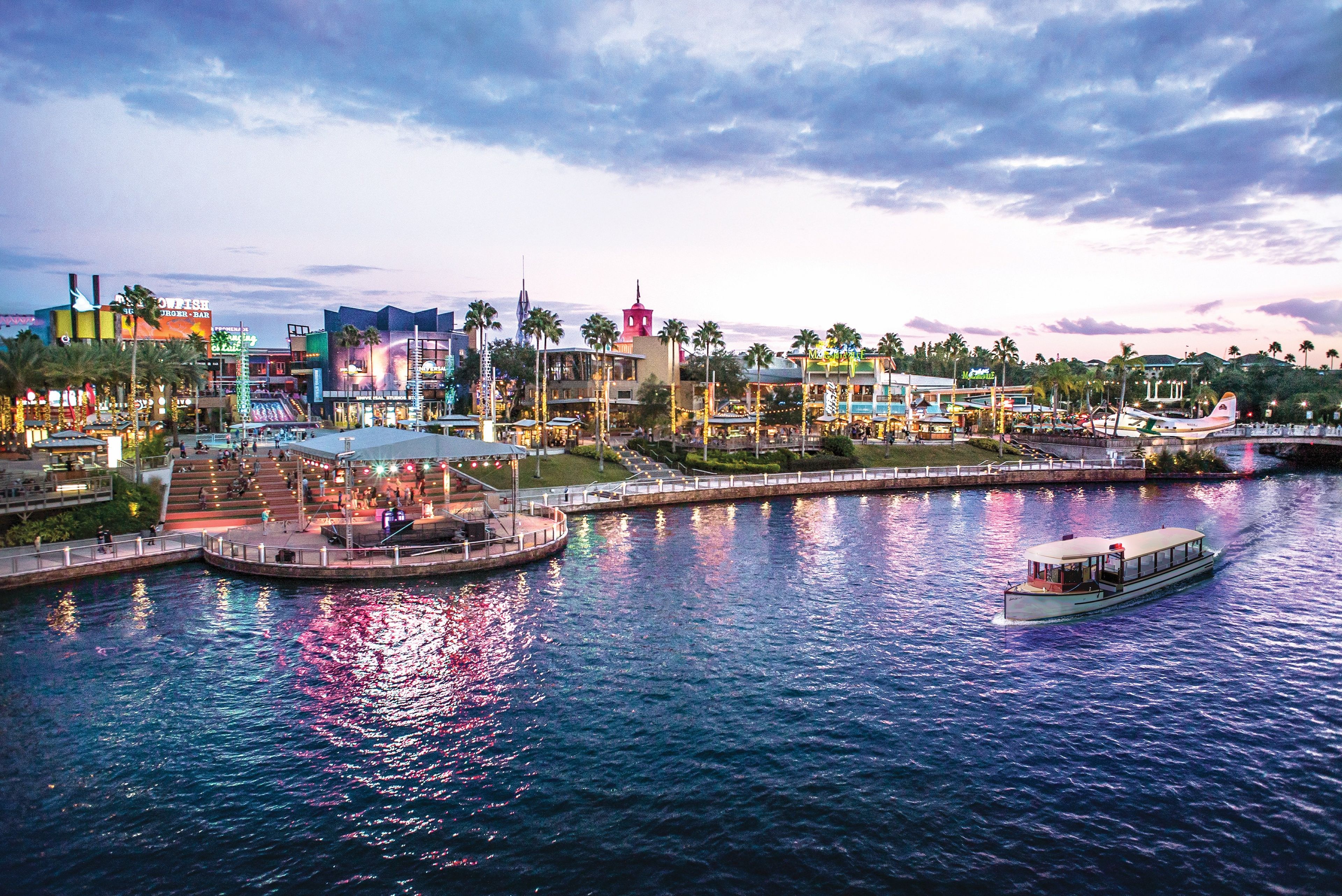 A waterfront area with a boat dock, a pedestrian bridge, and various buildings including a restaurant and a hotel.