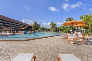 Una piscina al aire libre, sombrillas, sillones reclinables de piscina
