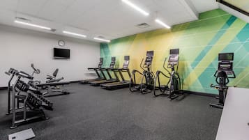 Un gimnasio con cintas de correr, elípticas y equipo de levantamiento de pesas.