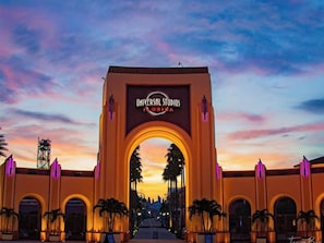 L’entrée d’Universal Studios Florida, avec une arche, des palmiers et un ciel au coucher du soleil.