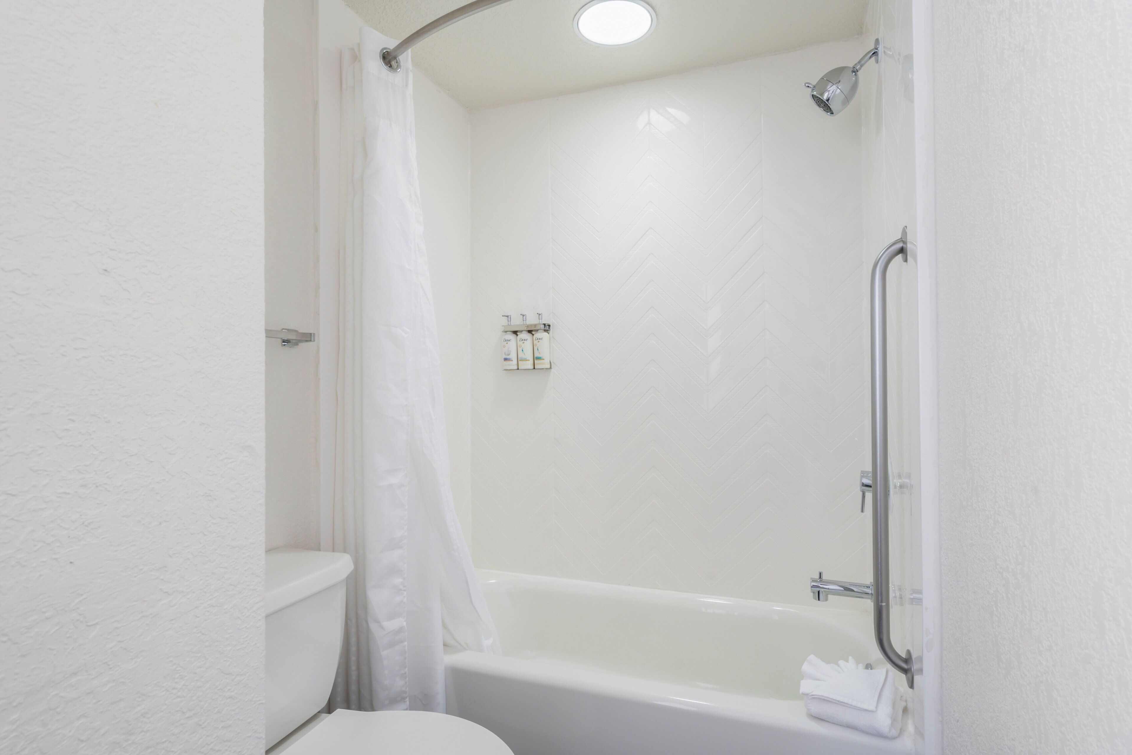 A bathroom with a white bathtub, a shower, and a toilet.