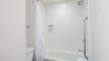 A bathroom with a white bathtub, a shower, and a toilet.