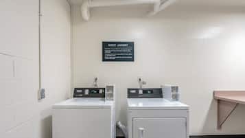 A guest laundry area with two Maytag washing machines, a sign with operating instructions, and a power outlet on the wall.