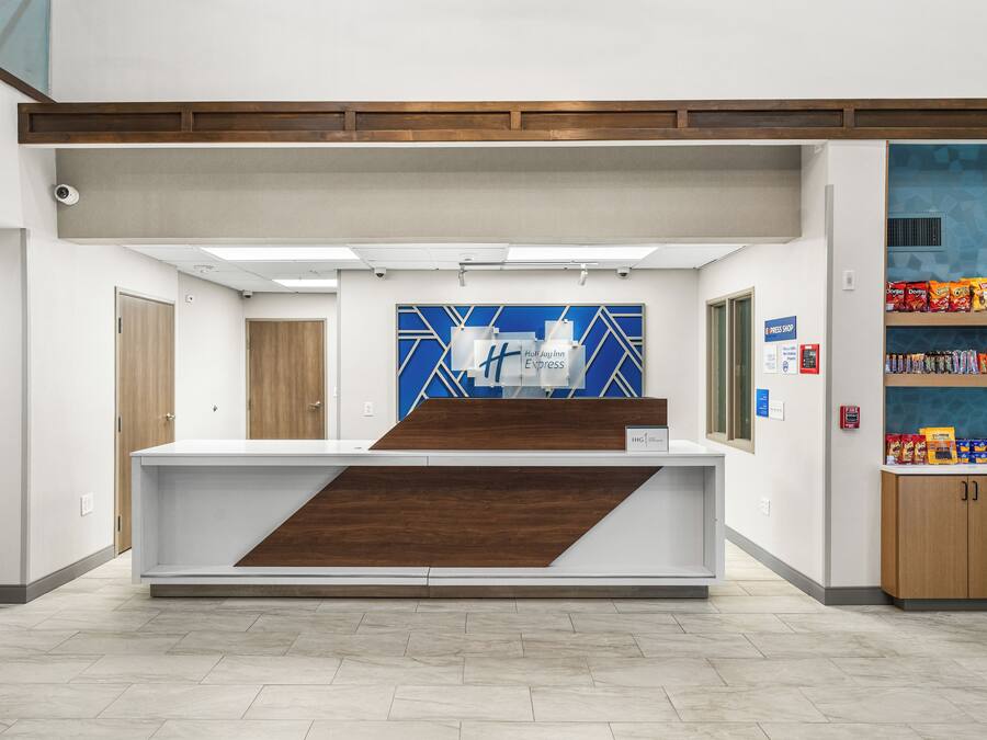 Una reception con un pannello murale geometrico blu e bianco, un estintore e uno scaffale per snack.