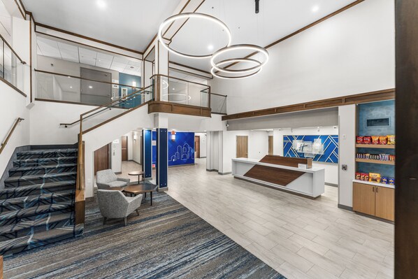 Un hall d’hôtel spacieux, doté d’un escalier, d’un espace salon et d’un comptoir d’accueil.
