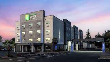 Un hotel Holiday Inn Express & Suites con un diseño moderno, que cuenta con un letrero llamativo y un estacionamiento.