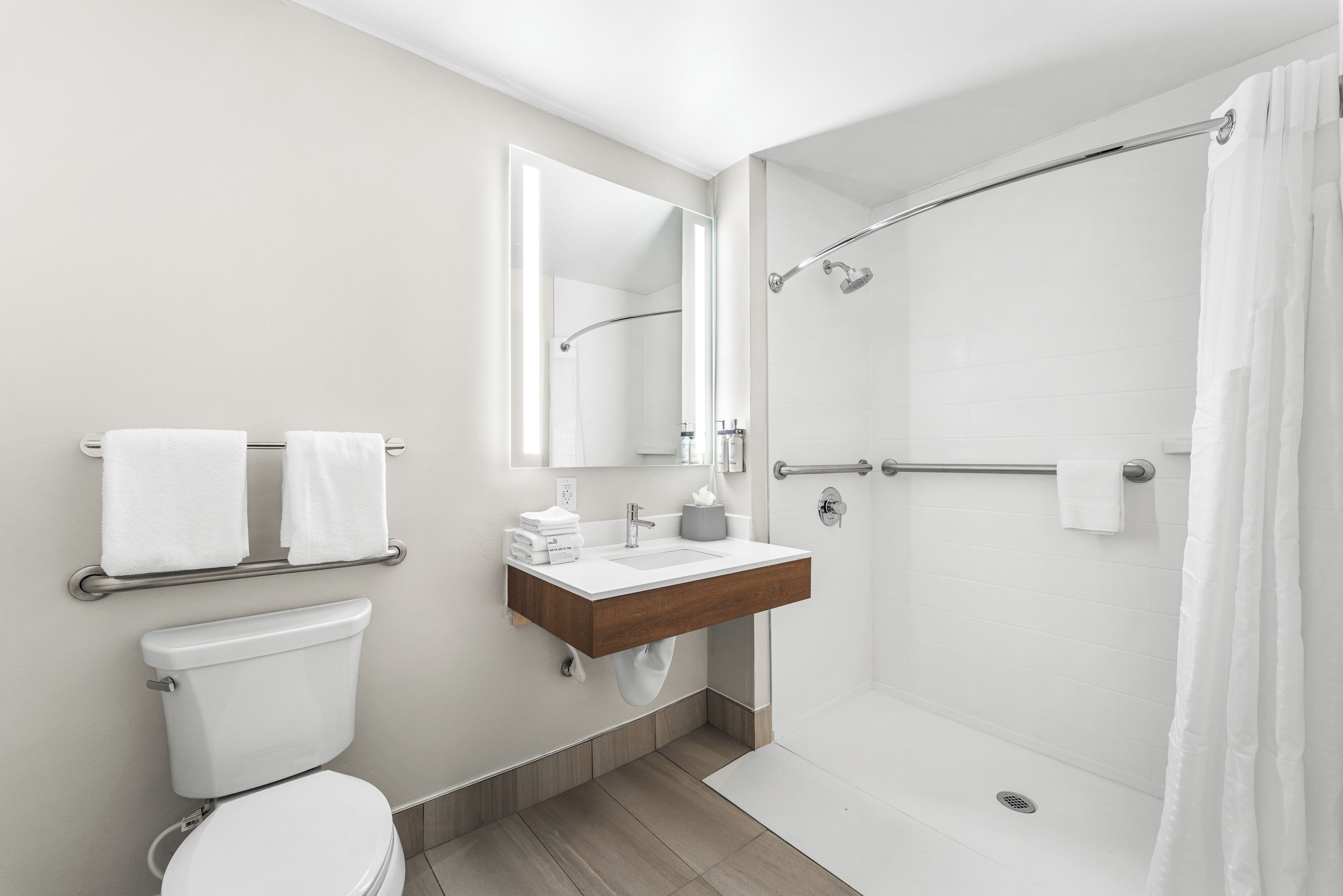 Un baño moderno con inodoro, lavamanos, espejo y ducha.