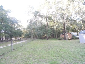 Surrounded by tall trees, this serene outdoor space features a well-manicured lawn and a paved path for easy access.