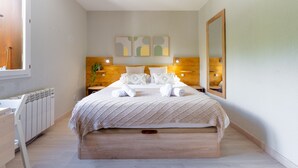 Ein Schlafzimmer mit Bett, Nachttischen, einem Heizkörper, einem Spiegel und abstrakter Wandkunst.