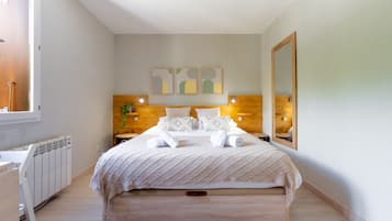 A bedroom with a bed, bedside tables, a radiator, a mirror, and abstract wall art.