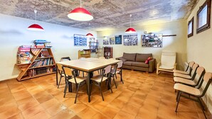 Ein gemütliches Zimmer mit Holztisch, Stühlen, einer Couch und einem Bücherregal.