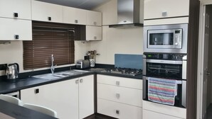 Eine moderne Küche mit weißen Schränken, einer Edelstahl-Dunstabzugshaube, einer Mikrowelle und einem Backofen.