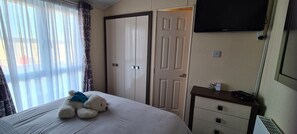 Een hotelkamer met een bed, een kledingkast, een televisie en een klein tafeltje.