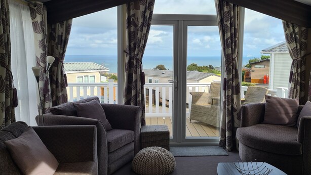 Ein Balkon mit zwei Sofas und einem Tisch, der auf einen Wohnbereich und das Meer blickt.