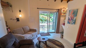 A living room with a sofa, a coffee table, and a ceiling fan. There is a sliding glass door leading to an outdoor area. - Peter Hytte is close to everything at great price! (Windward Side)