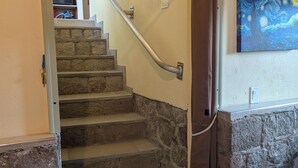 A staircase with stone steps and a metal handrail, leading to an upper floor. - Peter Hytte is close to everything at great price! (Windward Side)