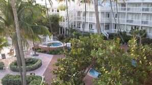 Un hotel de varios pisos con balcones, piscina y palmeras.