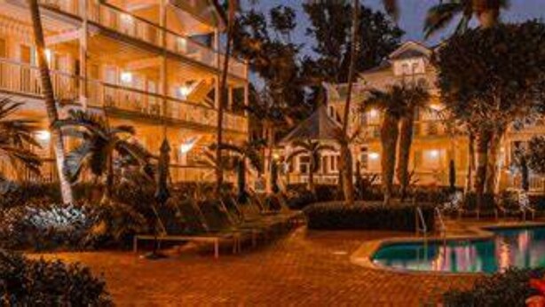 Un hotel con varias plantas, piscina y palmeras.