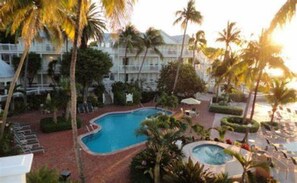 A resort with a swimming pool, palm trees, and a hot tub.