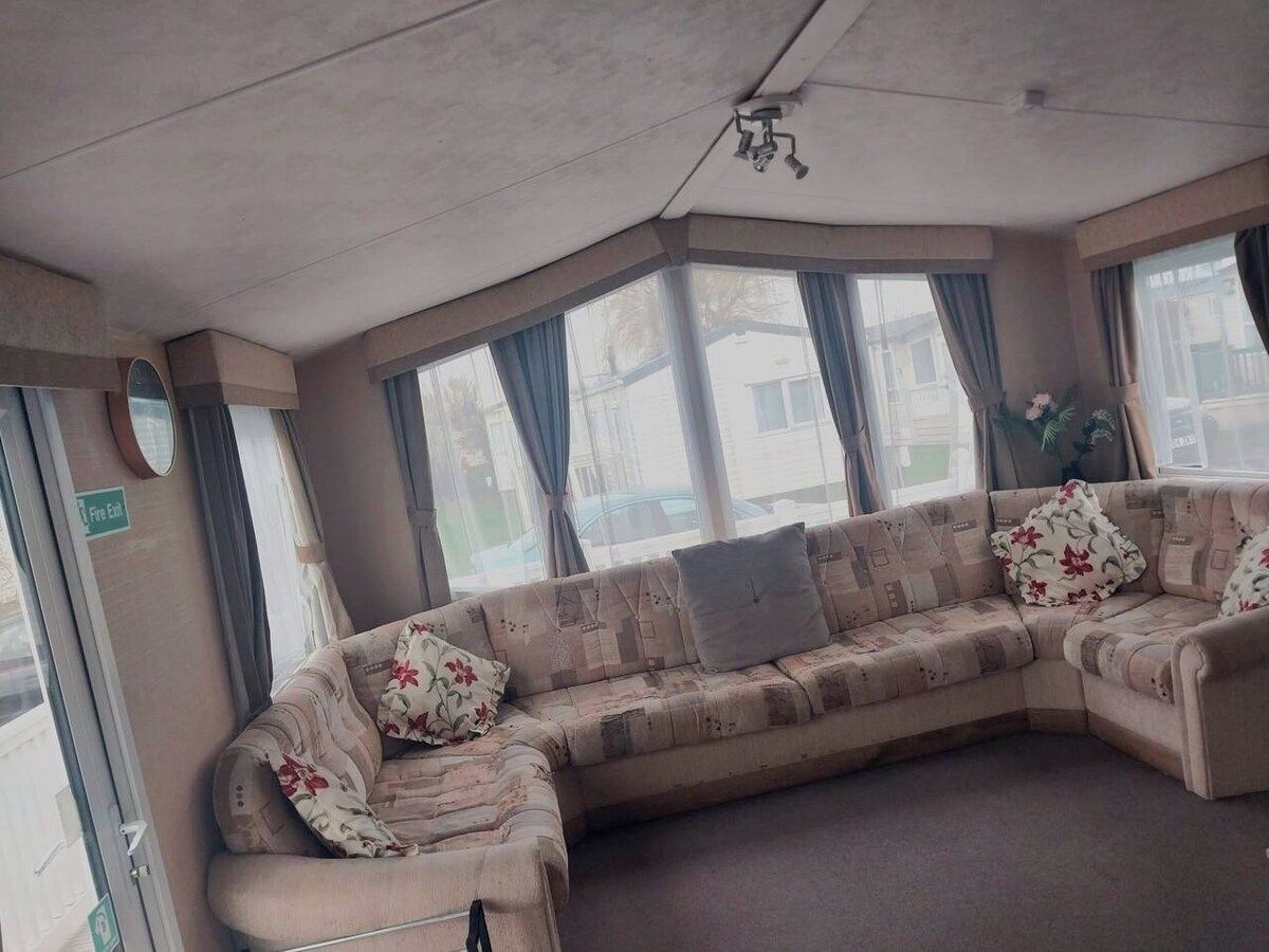 A corner living room with a sofa, a fire exit sign, and large windows.