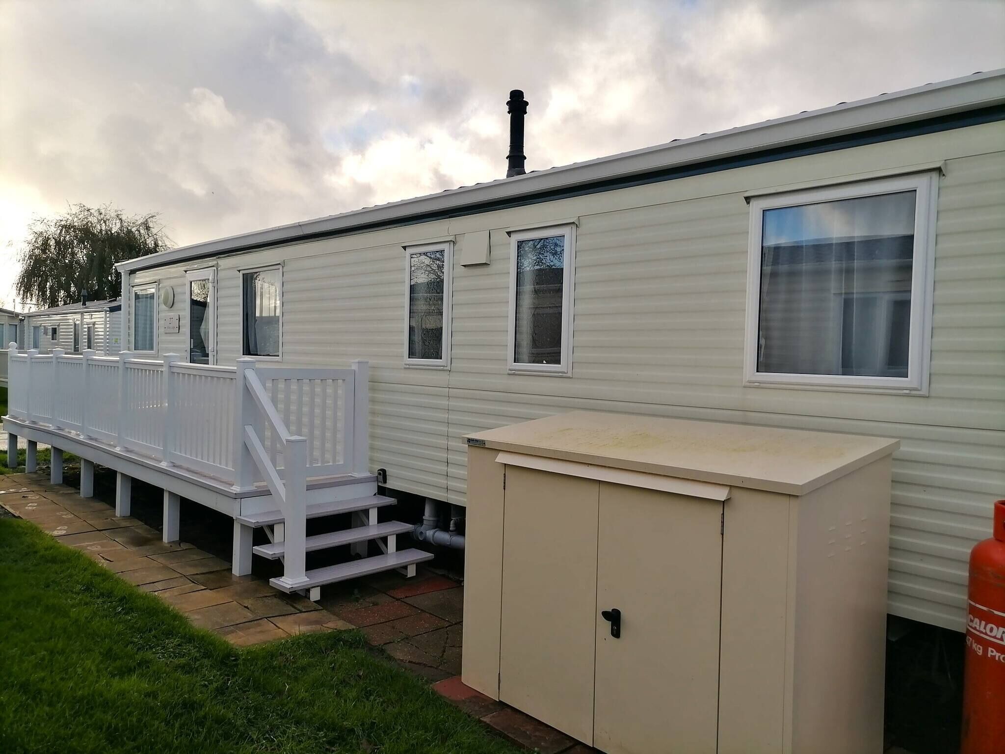 A row of mobile homes with white railings and a small step leading to the entrance.