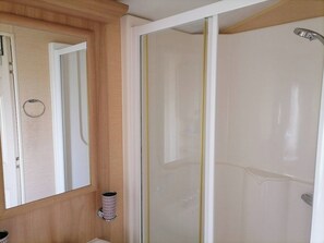 Une salle de bain avec une cabine de douche, un miroir et un porte-serviettes.