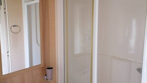 Un baño con tocador de madera, espejo, inodoro y ducha con puerta de vidrio.