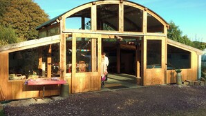 A wooden structure with large windows and a covered entrance. - Eco Glamping immersed in nature, ideal for family holidays andromantic getaways! (Whitegate)