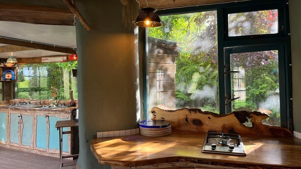 A rustic wooden bar with a unique design, a hanging pendant light, and a view of lush greenery outside. - Eco Glamping immersed in nature, ideal for family holidays andromantic getaways! (Whitegate)