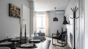 Een moderne eetruimte met een donker houten tafel gedekt voor vier personen, een zwarte hanglamp en een kapstok.