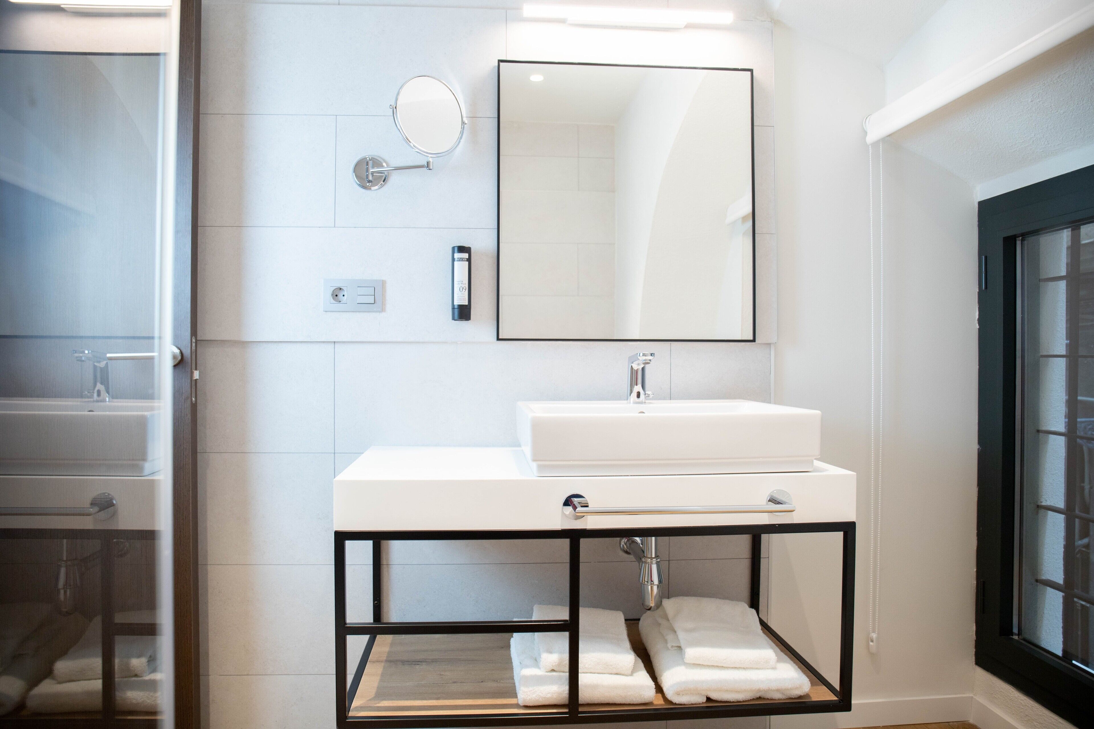 Une salle de bain moderne avec un lavabo blanc, un grand miroir et un porte-serviettes.