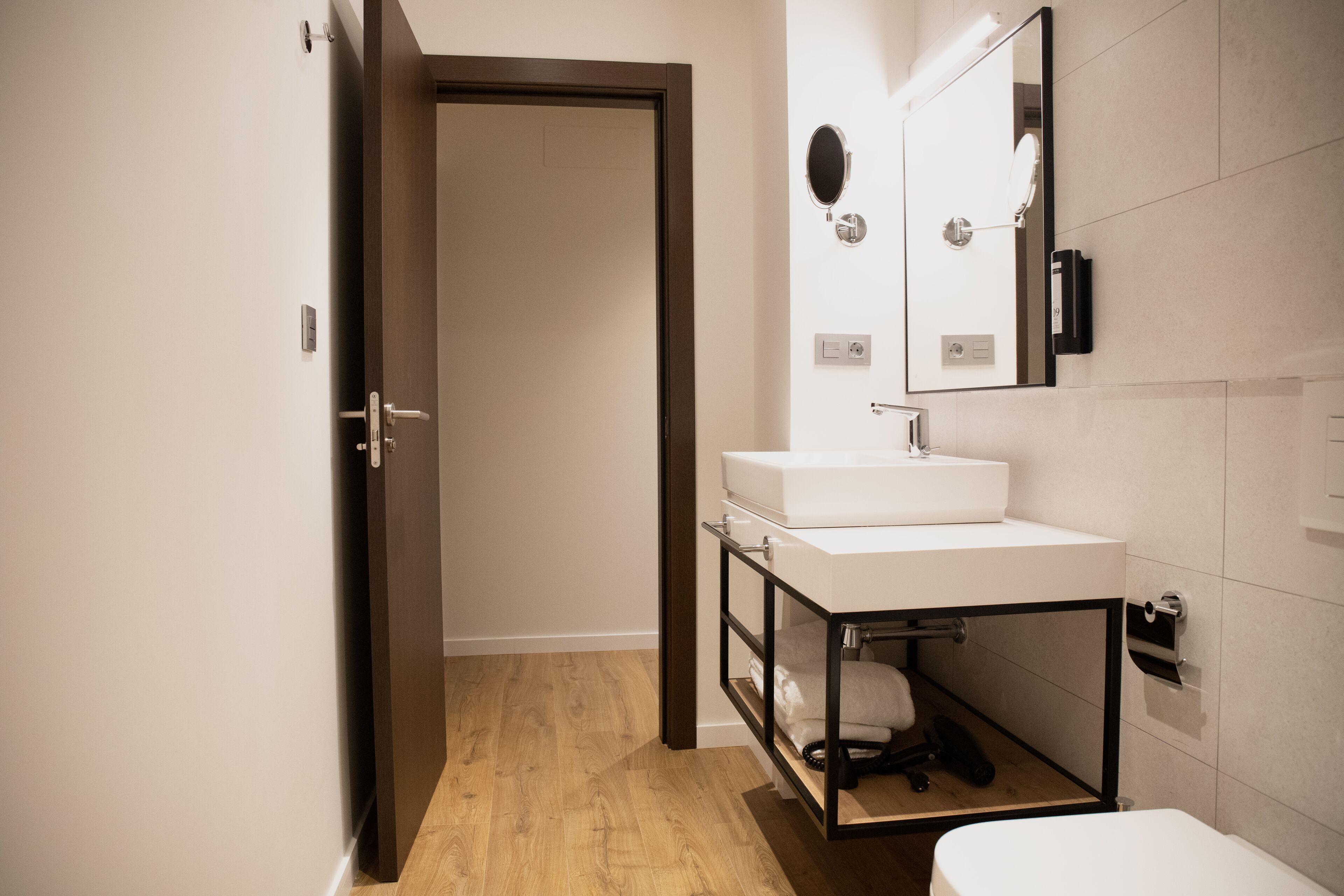 A modern bathroom with a white sink, a mirror, and a toilet.