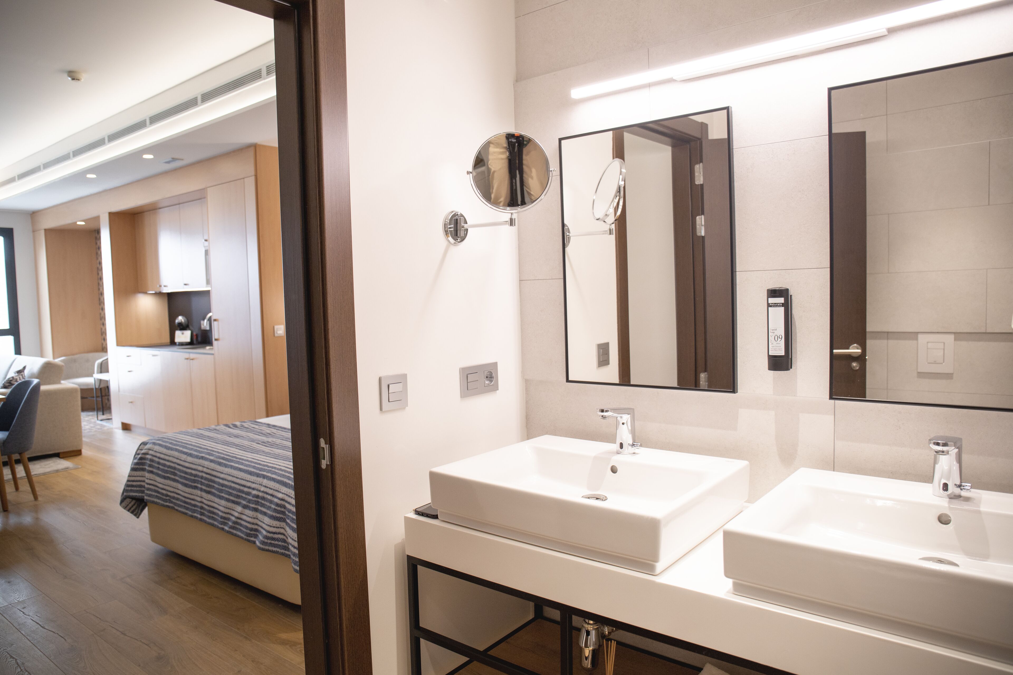 A modern bathroom with two sinks, a mirror, and a shower area.