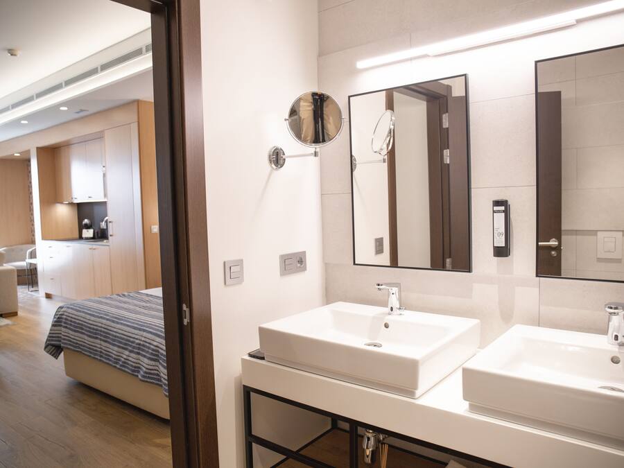 A modern bathroom with two sinks, a mirror, and a shower area.