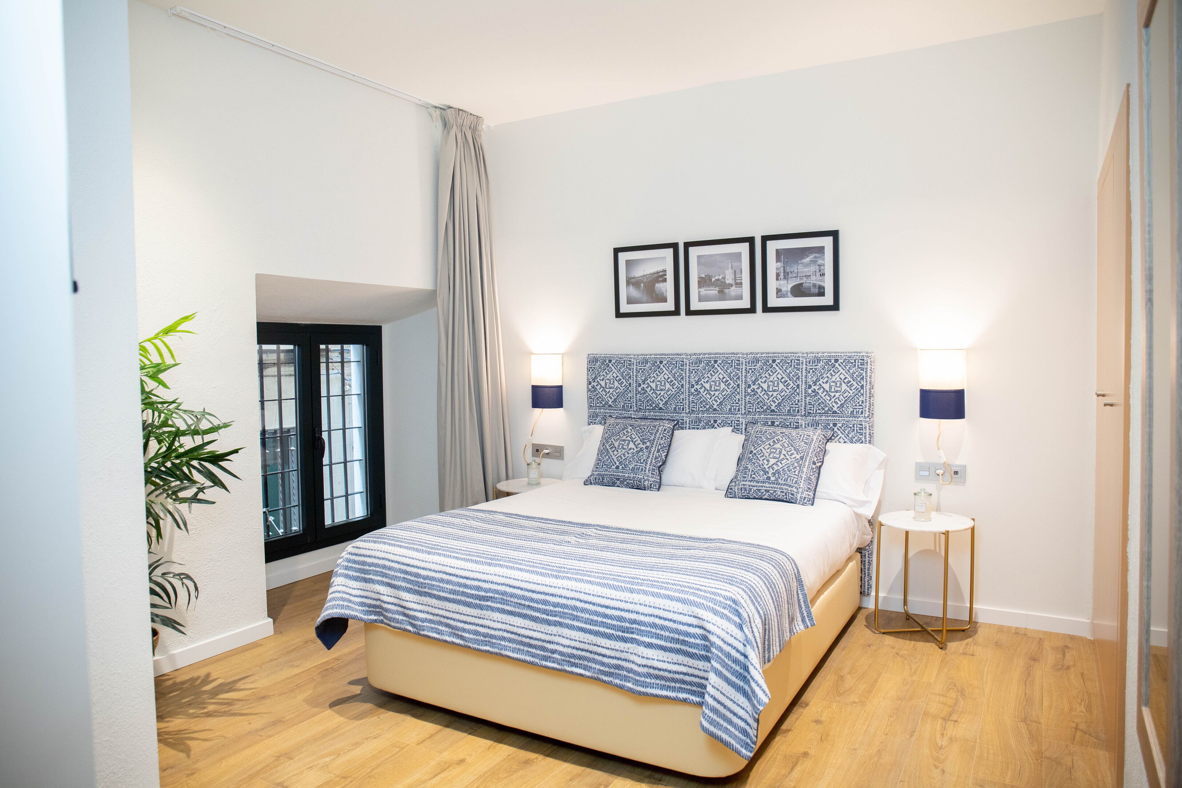 A modern bedroom with a large bed, a patterned headboard, and a small bedside table with a lamp.