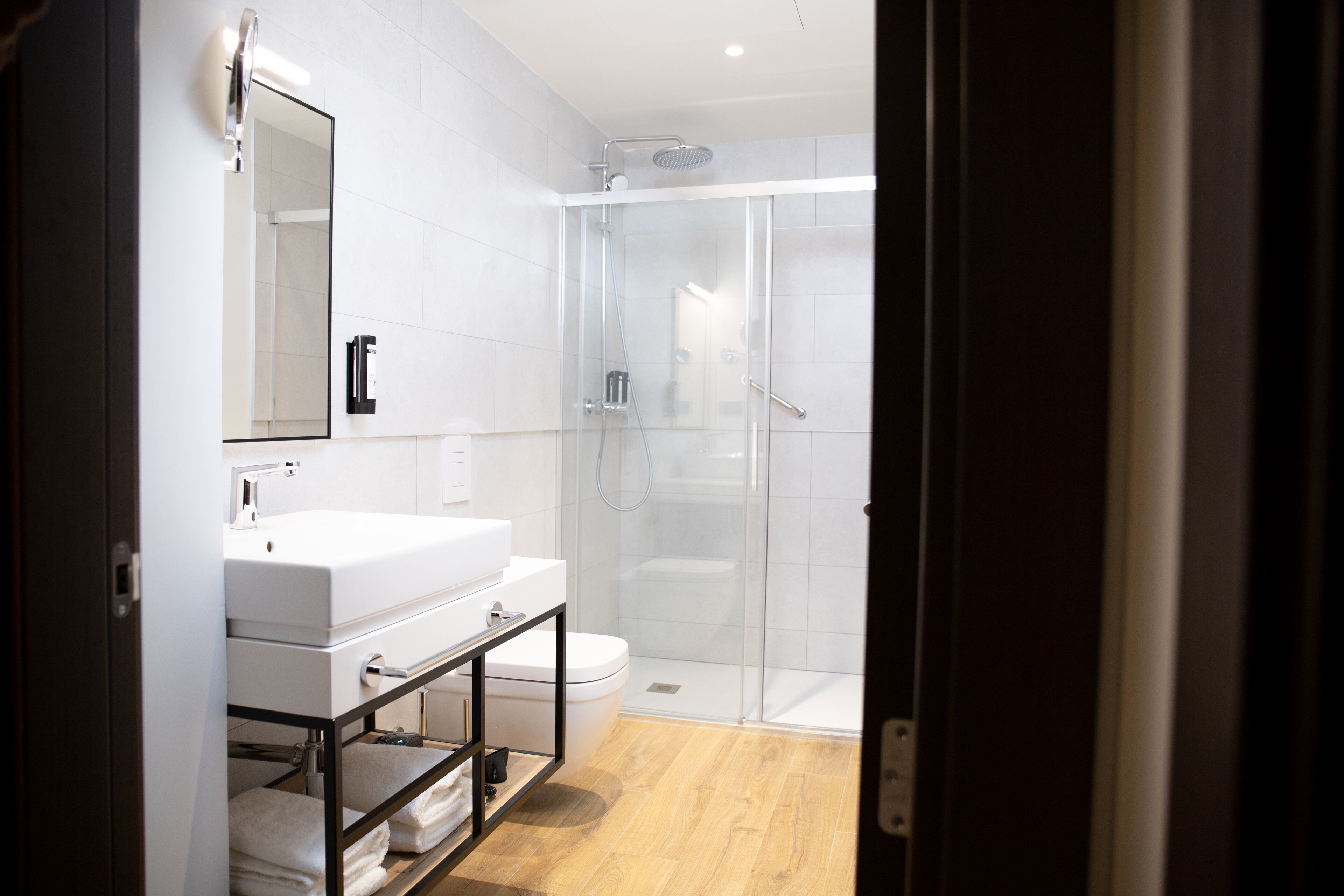 Un baño moderno con ducha de vidrio, lavamanos blanco y retrete.