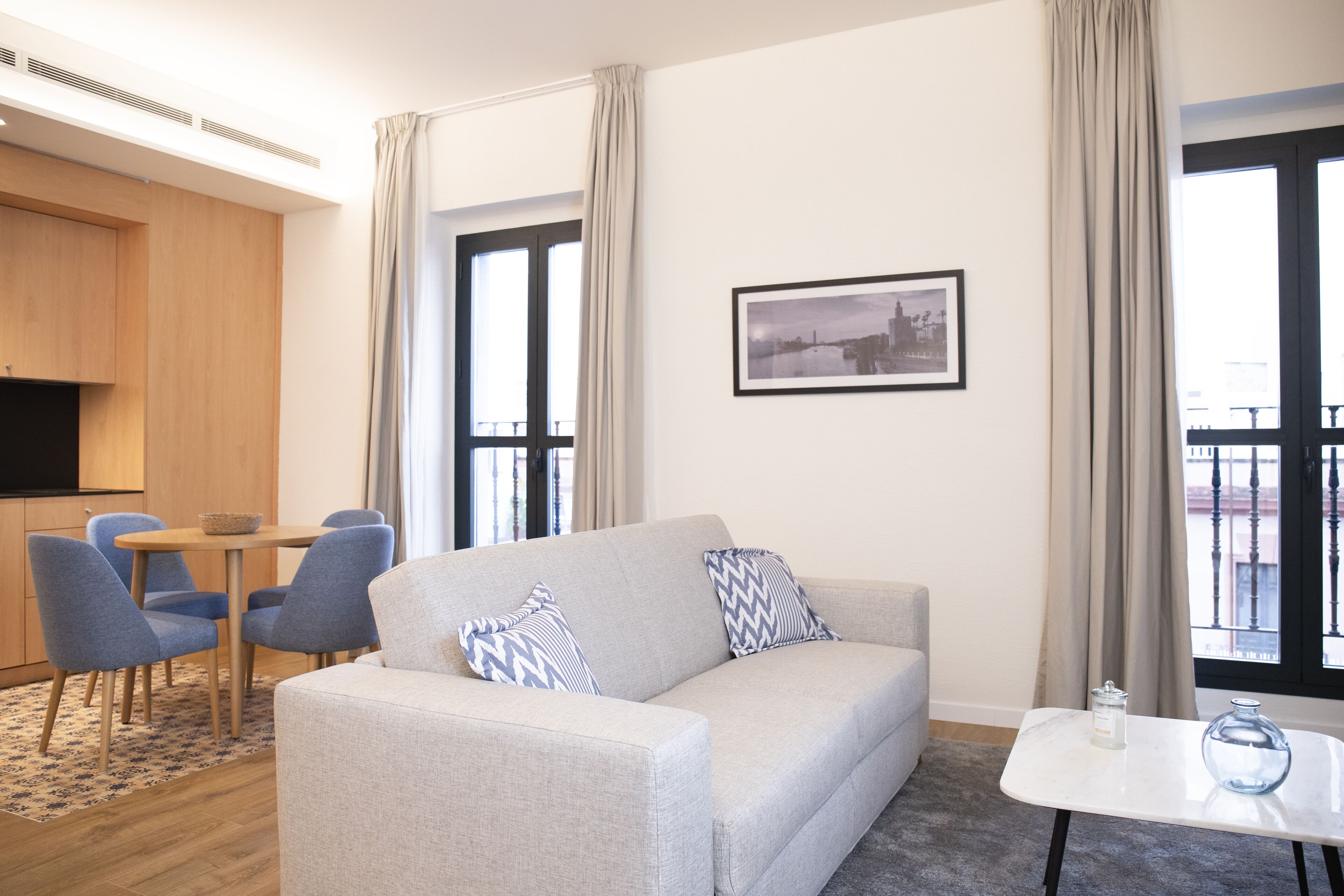 A modern living room with a sofa, chairs, a small table, and a picture on the wall.
