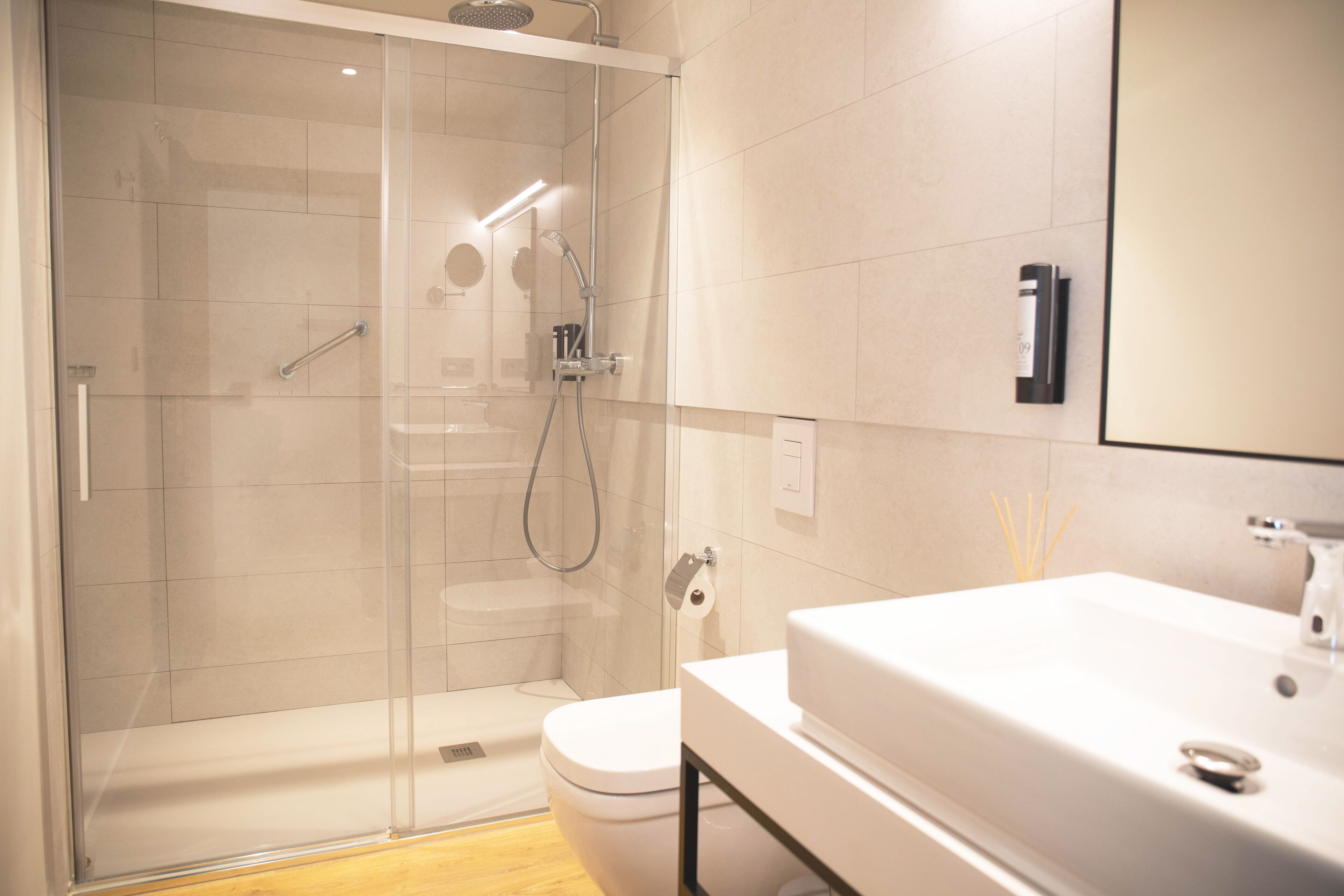 A modern bathroom with a glass-enclosed shower, a white toilet, and a large sink with a mirror above it.