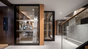 A modern interior with a glass door leading to a dining area, a staircase, and a reception desk. - nQn Aparts & Suites Sevilla (Seville)