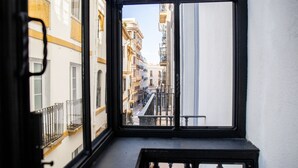 A view from a window with a black frame, looking out onto a street with buildings and a streetlight. - nQn Aparts & Suites Sevilla (Seville)