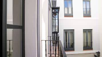 Un edificio con fachada blanca, barandillas negras y varias ventanas con cortinas.
