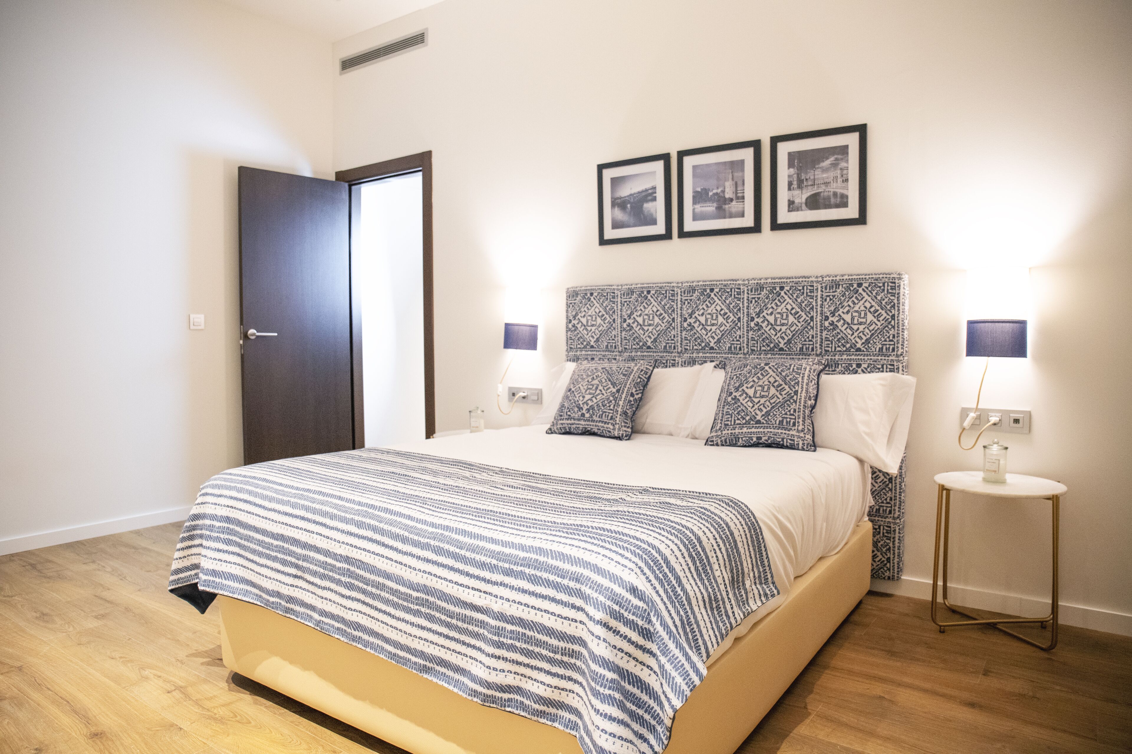 Un dormitorio con una cama, una mesita de noche, una lámpara y una puerta.