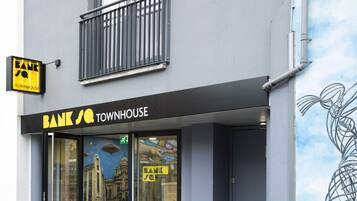 Un edificio con un letrero que dice "BANK TOWNHOUSE" y un mural en el lado derecho.