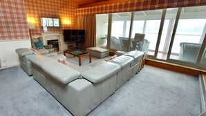 A living room with a sectional sofa, a fireplace, a television, and a view of the outdoors. - Loch Rannoch Highland Club Highland Lodge 33 (Kinloch Rannoch)