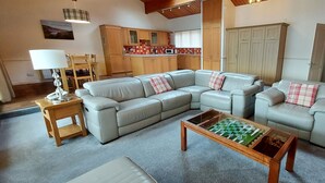 A living room with a sectional sofa, a wooden coffee table, and a small wooden side table. - Loch Rannoch Highland Club Highland Lodge 33 (Kinloch Rannoch)