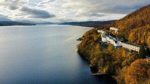 Une propriété située au bord d’un lac, avec un grand bâtiment, entourée d’un feuillage automnal et bordée d’un lac paisible.
