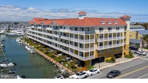 Ein mehrstöckiges Hotel mit Balkonen, eine Marina mit Booten und ein klarer Himmel.