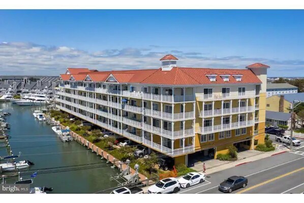 Un hôtel à plusieurs étages doté de balcons, une marina avec des bateaux et un ciel dégagé.