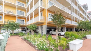 Ein mehrstöckiges Hotel mit Balkonen, einer Tiefgarage und einem angelegten Garten.